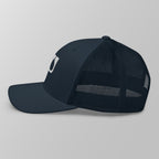 Side view of a navy blue premium padel trucker cap with breathable mesh panels.