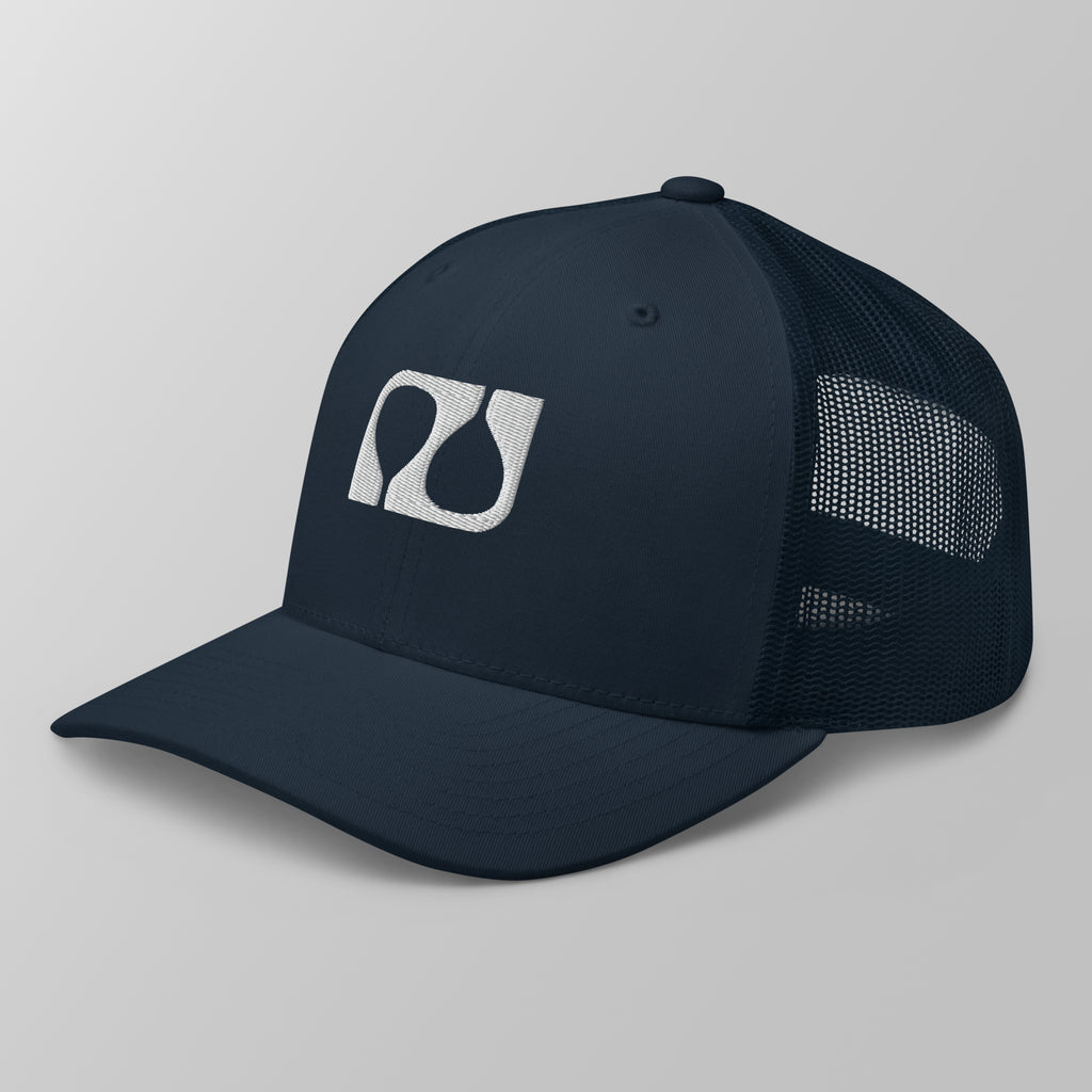 Angled view of a navy blue premium padel trucker cap featuring a white embroidered 'Après Padel Society' logo.