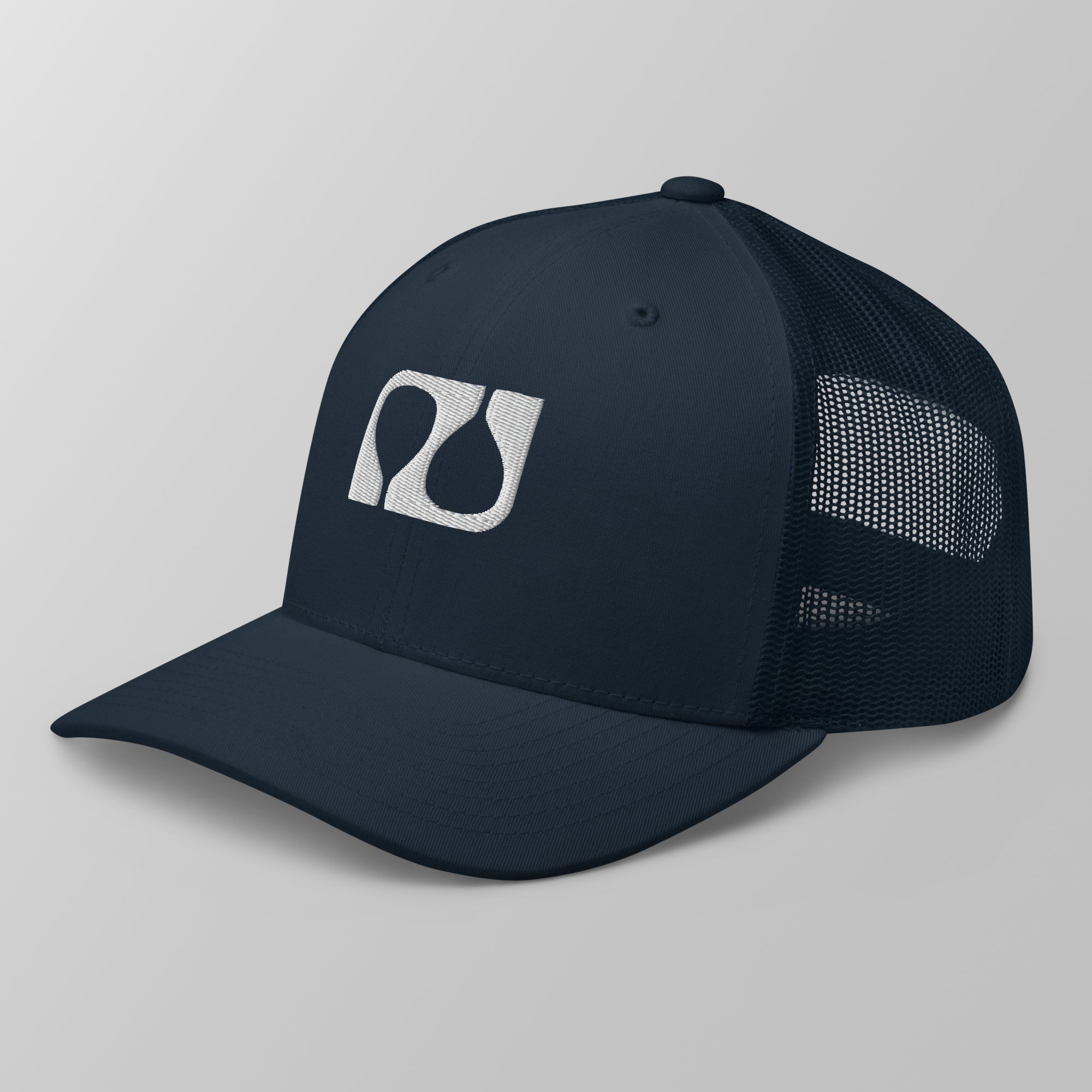 Angled view of a navy blue premium padel trucker cap featuring a white embroidered 'Après Padel Society' logo.