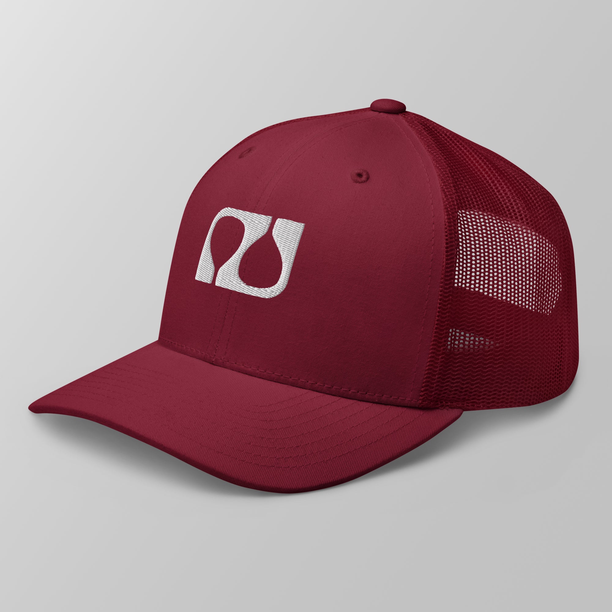 Angled view of a maroon premium padel trucker cap featuring a white embroidered 'Après Padel Society' logo.