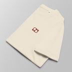 Close-up of a folded cream padel t-shirt with a small red logo on the left chest.