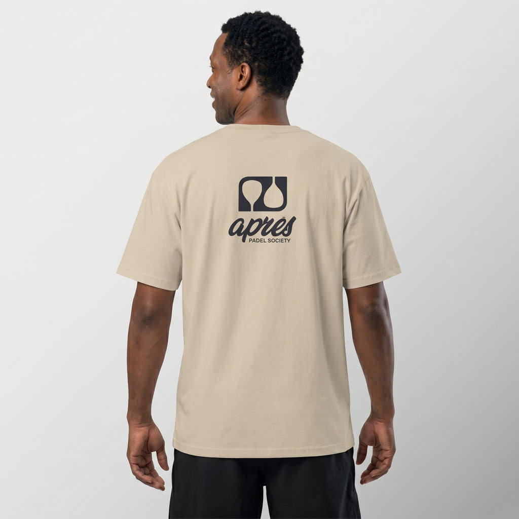 Male model with back toward camera wearing an oversized ecru unisex padel t-shirt in relaxed fit with a black logo central on the back.