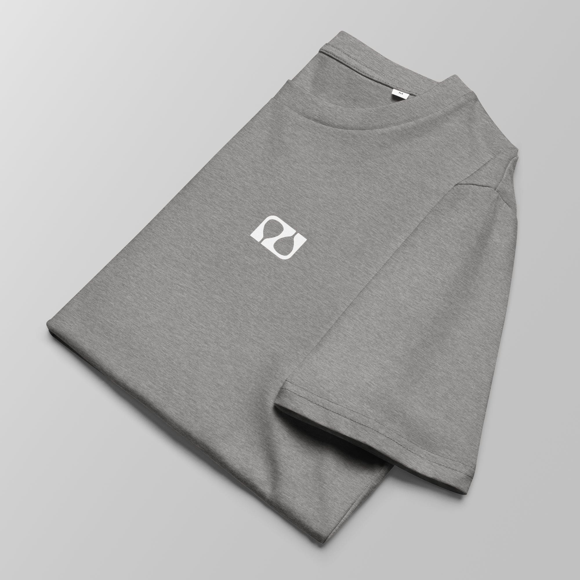 Close-up of a folded heather grey padel t-shirt with a small white logo on the left chest.