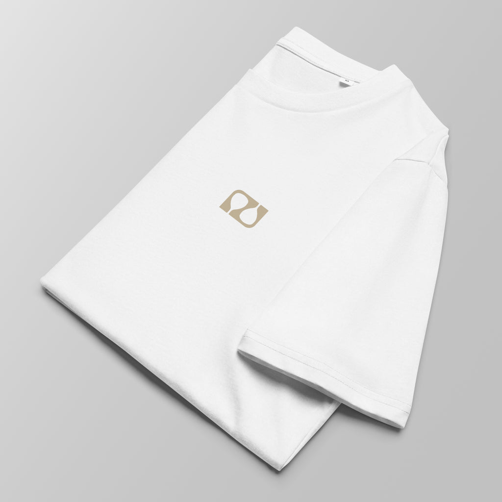 Close-up of a folded white padel t-shirt with a small tan logo on the left chest.