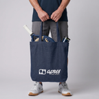 Model carrying a premium navy padel tote bag with visible padel racket and balls inside, featuring a white 'Après Padel Society' logo.