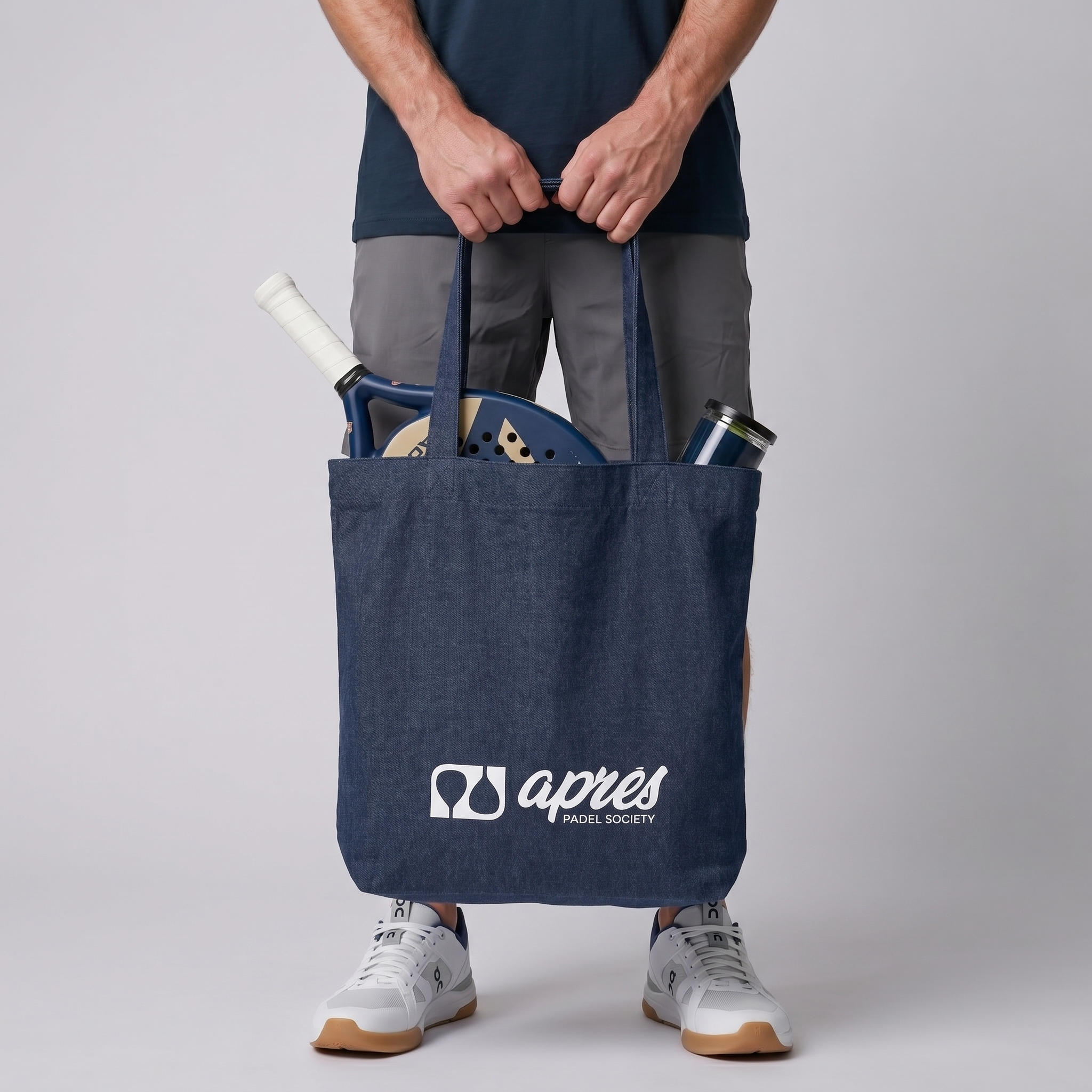 Model carrying a premium navy padel tote bag with visible padel racket and balls inside, featuring a white 'Après Padel Society' logo.