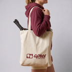 Model carrying a premium cream padel tote bag with visible padel racket and water bottle inside, featuring a red 'Après Padel Society' logo.
