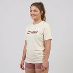 Female model wearing an oversized unisex cream padel t-shirt in relaxed fit with a red horizontal chest logo.
