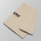 Close-up of a folded ecru padel t-shirt with black 'Après Padel Society' logo centred.