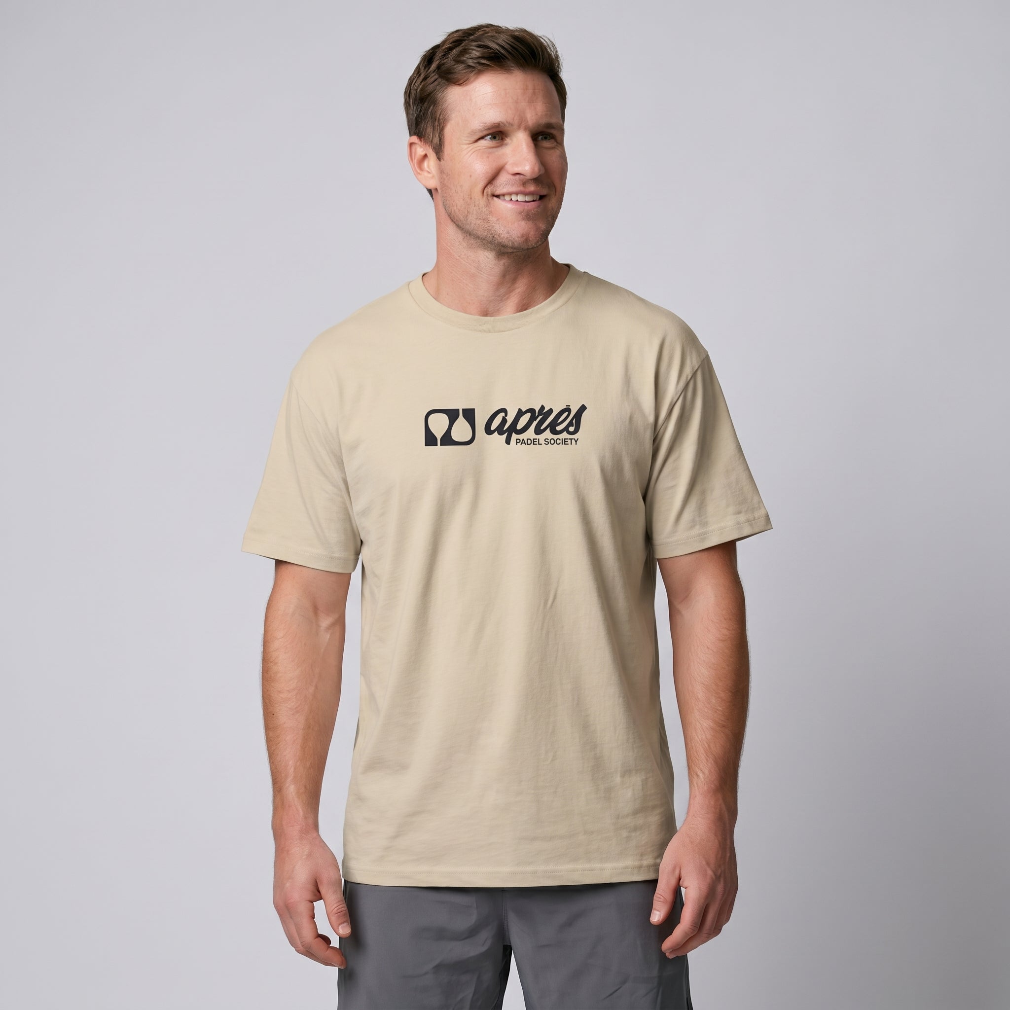 Male model wearing an oversized unisex ecru padel t-shirt in relaxed fit with a black horizontal chest logo.