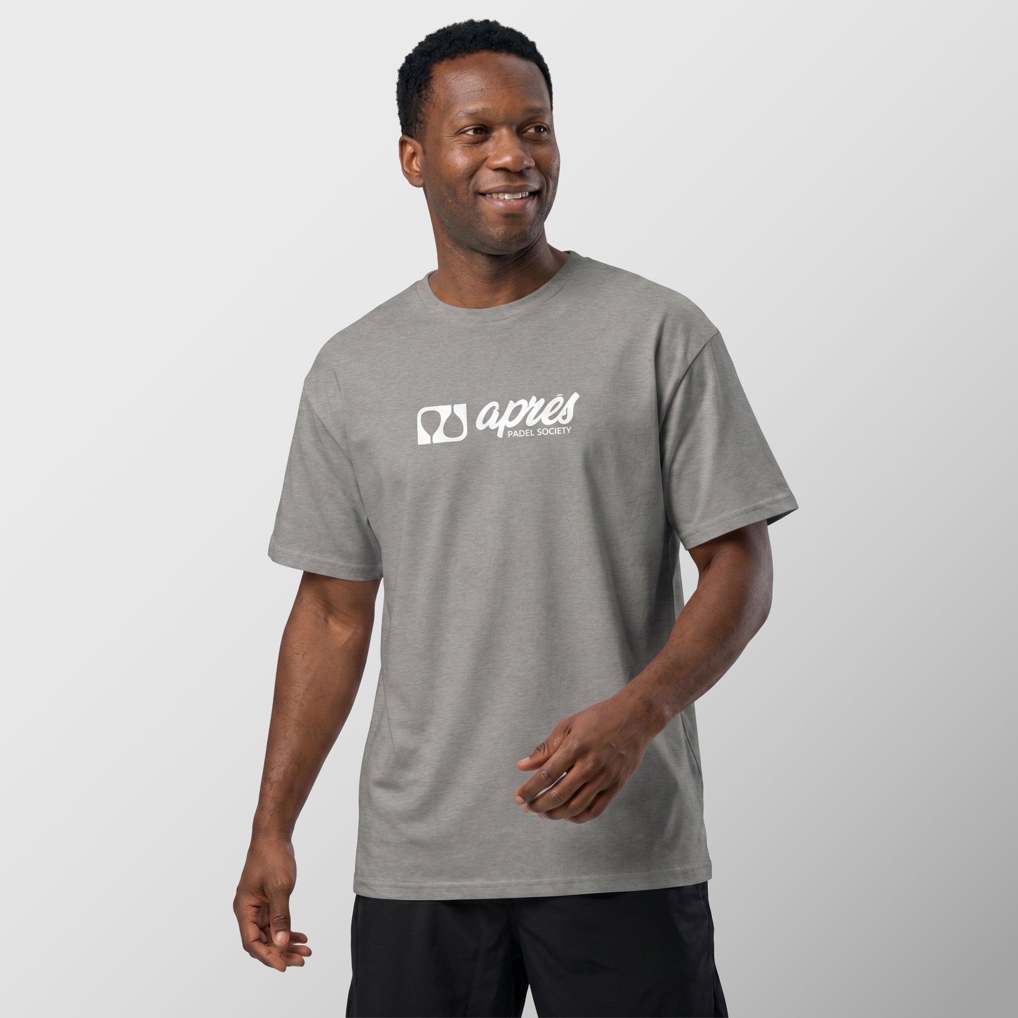 Male model wearing an oversized unisex heather grey padel t-shirt in relaxed fit with a white horizontal chest logo.