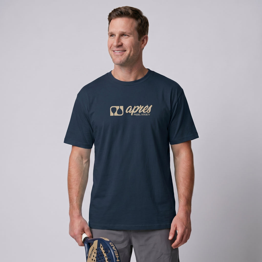 Male model wearing an oversized unisex navy blue padel t-shirt in relaxed fit with a tan horizontal chest logo.