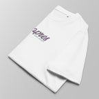Close-up of a folded white padel t-shirt with the green and purple 'Après Padel Society' logo centred.