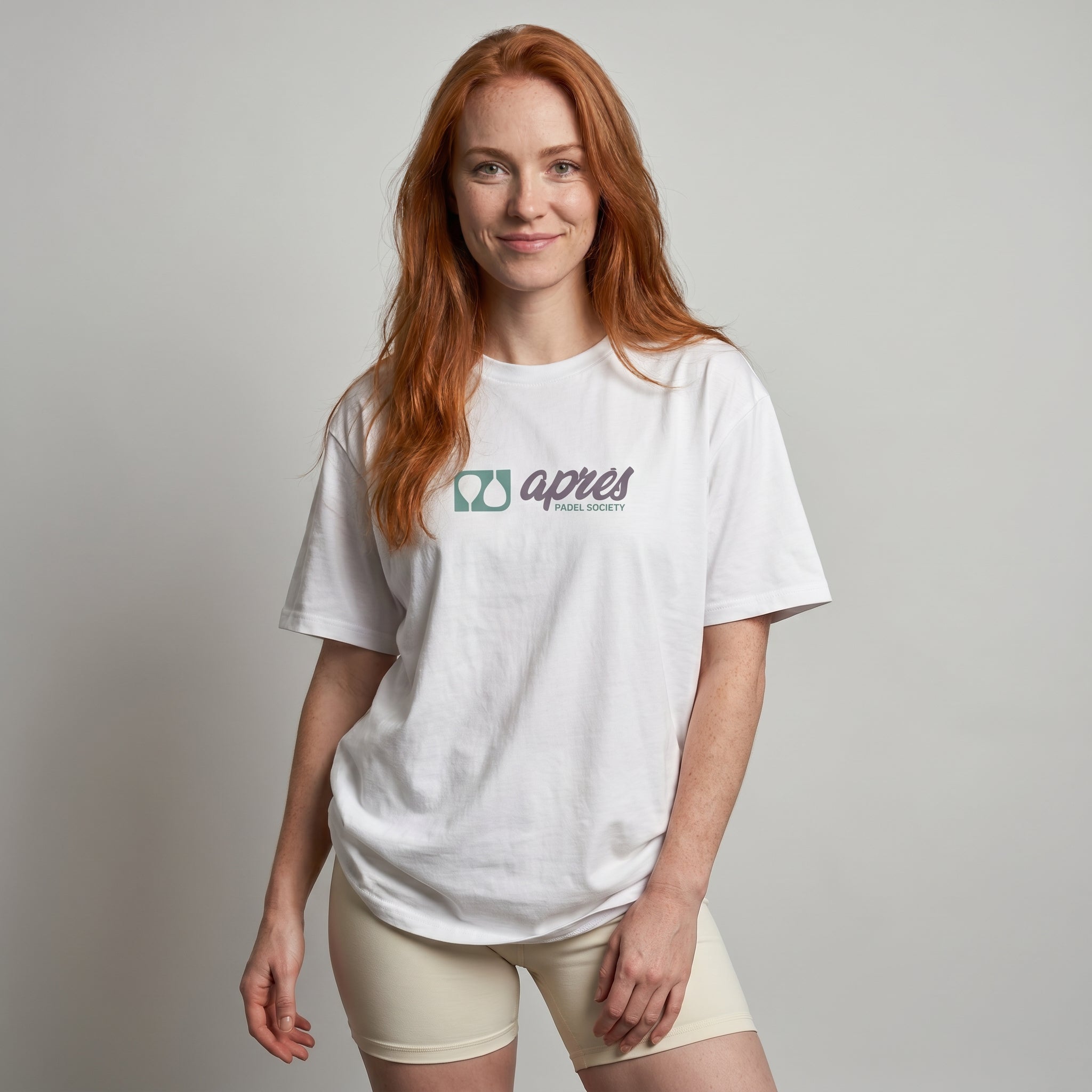 Female model wearing an oversized unisex padel t-shirt in relaxed fit with green and purple horizontal chest logo.