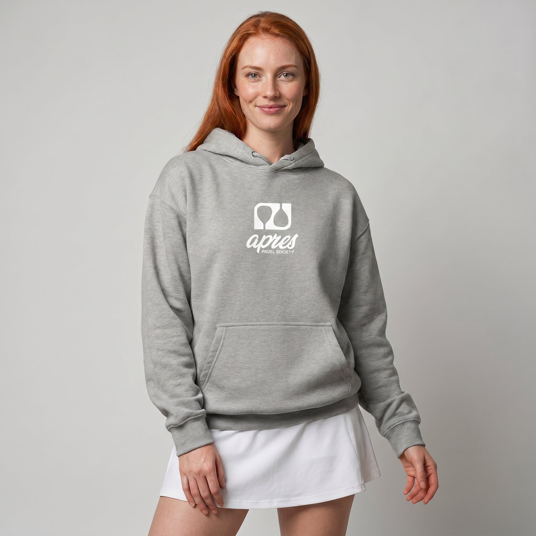 Woman modelling a heather grey premium padel hoodie with a white 'Après Padel Society' logo.